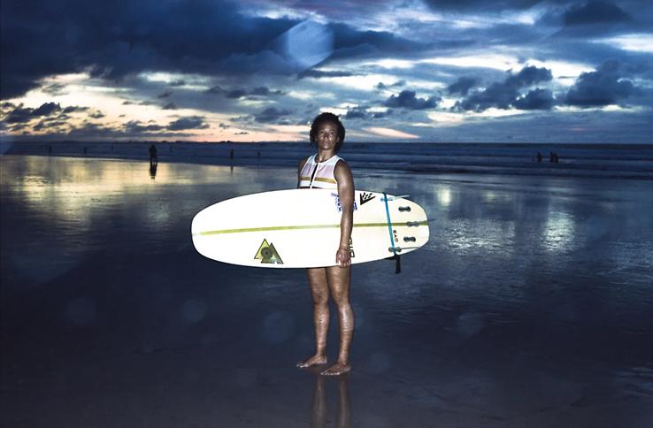 surfer posing board in hand at sunset